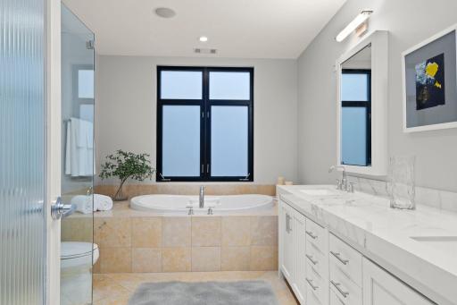 Refreshed Primary Bathroom with Bain Ultra Tub for an at-home spa experience and privacy glass on the windows