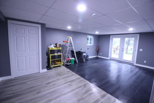 Bedroom #5, 23'x14', currently being used as a workshop. Door on left is a closet. Double doors go outside. !/2 the floor is vinyl plank and the other black rubber diamond plate tiles. Home office, business or studio aptmt. Unlimited possibilities.