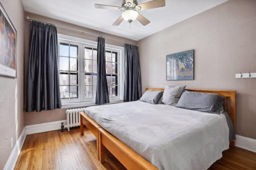 Spacious bedroom with beautiful hardwood floors and picturesque windows.