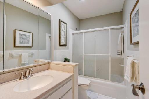 Shared full bathroom with tile floors and tub/shower combo.