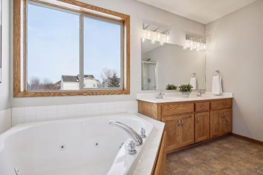 Spacious primary bathroom with jetted tub, walk in shower, and double vanity