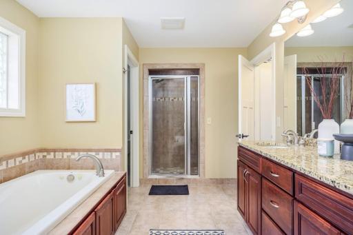 Double vanity, soaking tub, and walk-in shower. Pristine neutral tile and granite countertops.