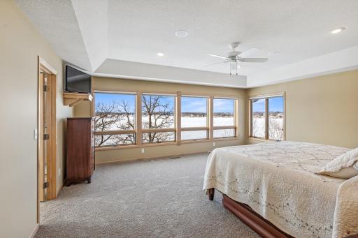 An impressive primary suite overlooks the lake, complete with tray vault ceiling, walk in his and hers closets with shelving/organizer and opulent bath.