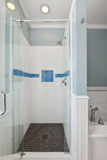 Large walk in shower with glass door and custom tile highlights this remodeled bathroom