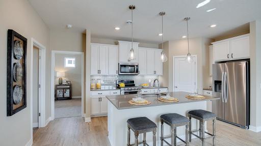Open concept kitchen with ample countertop space and a large corner pantry. Model photo. Options and colors will vary. See listing agent for home specific selections.