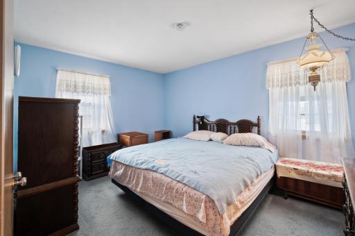 Huge primary bedroom (shown with a king sized bed) features hardwood floors and two windows.