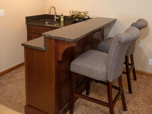 The wet bar has ample cabinet space and granite counter tops