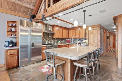 Gourmet kitchen with stylish stone flooring and backsplash, professional appliances and concrete countertops