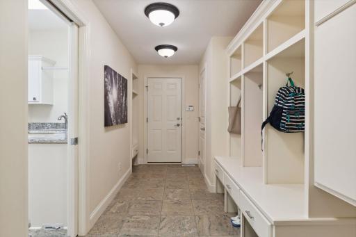 Mudroom is entered from the 3-car garage. Main floor laundry with sink is off to the left in this photo through the pocket door