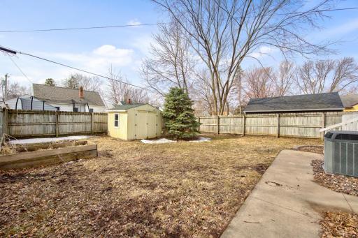 fenced in yard with storage shed and raised garden