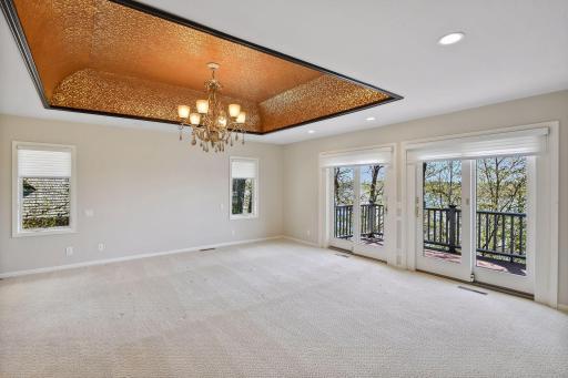 Bright and sunny primary bedroom features a private deck and 14k gold inlaid tray ceiling