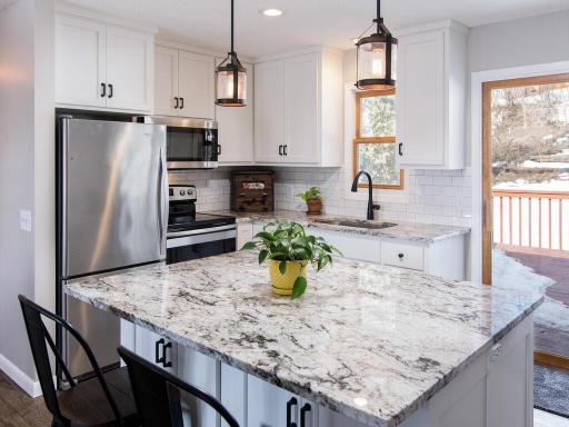 Kitchen features granite counters, large island, new stainless appliances, backsplash, updated cabinets & light fixures