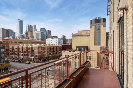 A wide main level balcony provides fresh air, a city skyline view, container gardening, and room for seating.