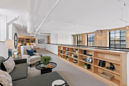 Upper mezzanine level lounge with built-in library shelving and skyline views.