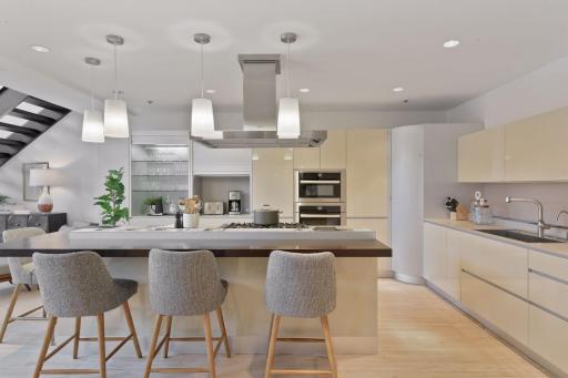 The european-style designer kitchen features accessorized cabinetry and storage, hidden appliance and bar cabinets, a corner pantry, and a large center island with seating.