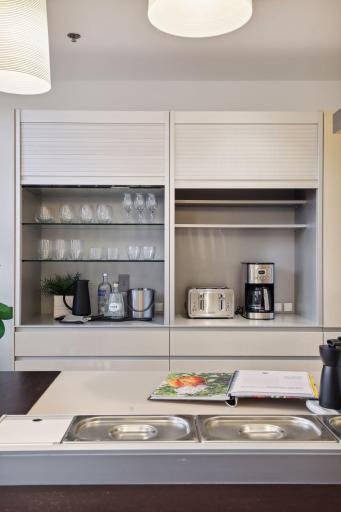 Illuminated bar and appliance cabinetry with top-down sliding doors.