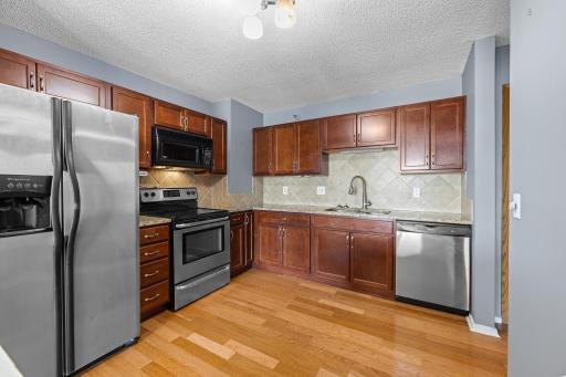 Updated kitchen with stainless steel appliances, back splash and wood flooring.