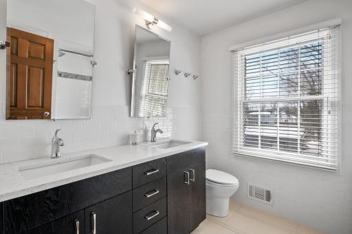 Upper-level full bathroom with dual sinks and subway-tiled backsplash, wall, and tub surround.