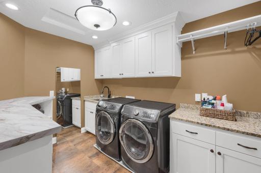 Upper level laundry room has an abundant amount of built-in storage, folding areas, and utility sink