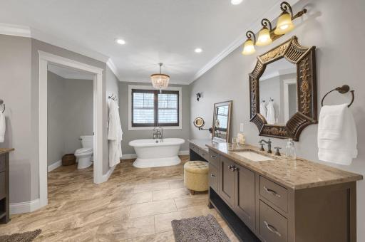 Excuisite bathroom with soaking tub, individual vanities, and private toilet room