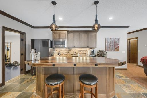 Lower level wet bar with full sized refrigerator, beverage refrigerator, microwave, and plenty of built-in storage