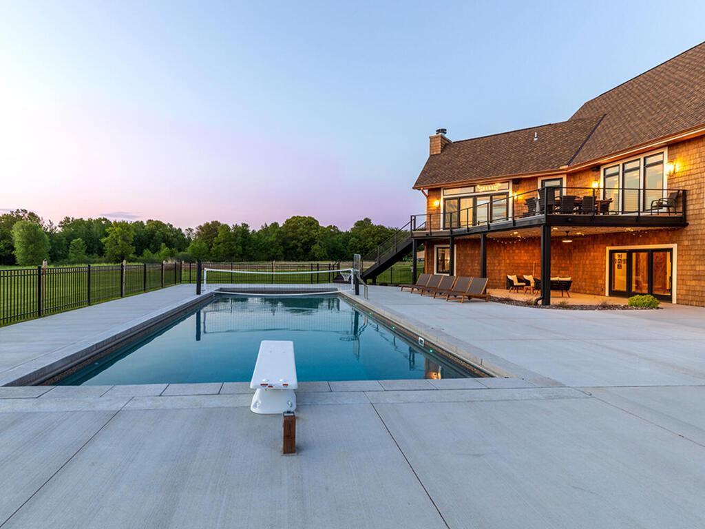 Fenced in pool area with diving board and volleyball net.