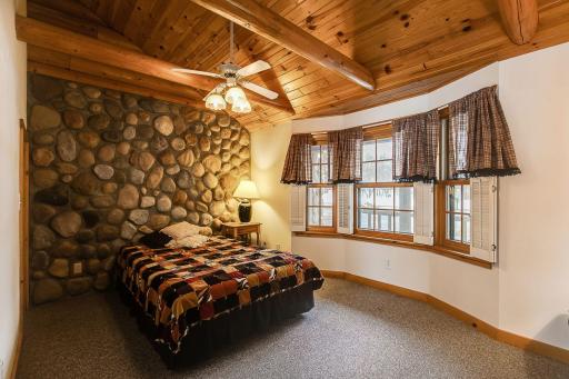 Main floor bedroom with log beams and a vaulted ceiling