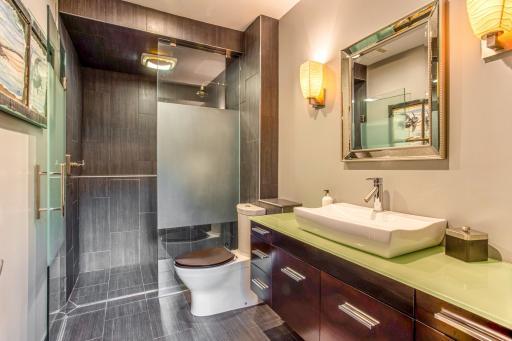 Main-floor Bathroom with modern vanity, a walk-in tile shower, & heated floors (separately zoned).