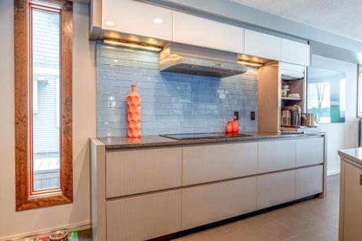 Eat-in Kitchen with custom European-designed cabinets with tons of storage, soft-close pantry doors with pull-out drawers, a built-in Gaggenau fridge, Electrolux appliances, a Barista Station, & modern articulating Karbon joystick faucet.