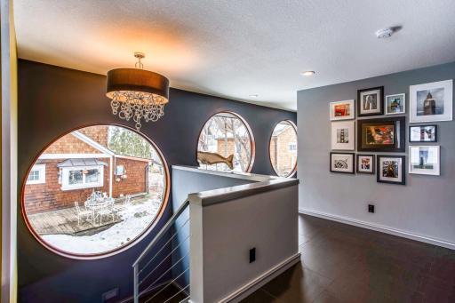 Gorgeous staircase leading upstairs highlighted by the stainless-steel cabling, and the spectacular 7' Anderson circular window, plus two additional 6' circular windows down the hallway.