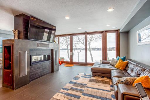 Bright and open Living Room with see-thru fireplace with remote, wall-to-wall, floor-to-ceiling Anderson sliding door & windows which open 8’ wide, heated porcelain tile flooring, plus a built-in Bowers and Wilkins Surround Sound System