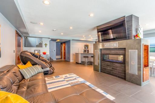 Bright and open Living Room with see-thru fireplace with remote, wall-to-wall, floor-to-ceiling Anderson sliding door & windows which open 8’ wide, heated porcelain tile flooring, plus a built-in Bowers and Wilkins Surround Sound System