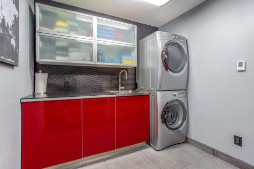 Spacious Laundry Room with stackable Electrolux front-load Washer/Dryer with steam, plus a deep-well stainless-steel sink with plenty of counter space and cabinet space above and below. Tons of storage room in the coat closet too!