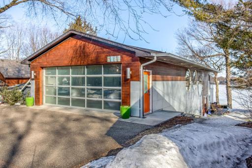 Oversized 2.5 stall heated Garage with 20' see thru Garage Door, floor drain, overhead storage, softened hot and cold water spigots, and a 10 gallon Air Compressor above with ceiling mounted retractable hose reel.