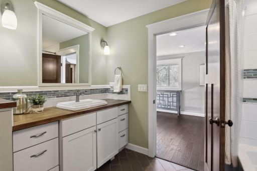 The main level primary suite's full bathroom has loads of storage and a spacious layout.