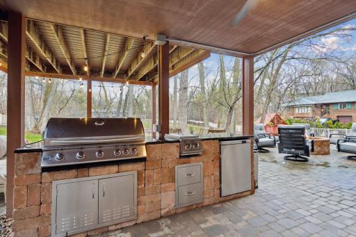 Outdoor Kitchen with Commercial Gas Grill, Gas Stoves, Refrigerator next to Gas Firepit & Seating