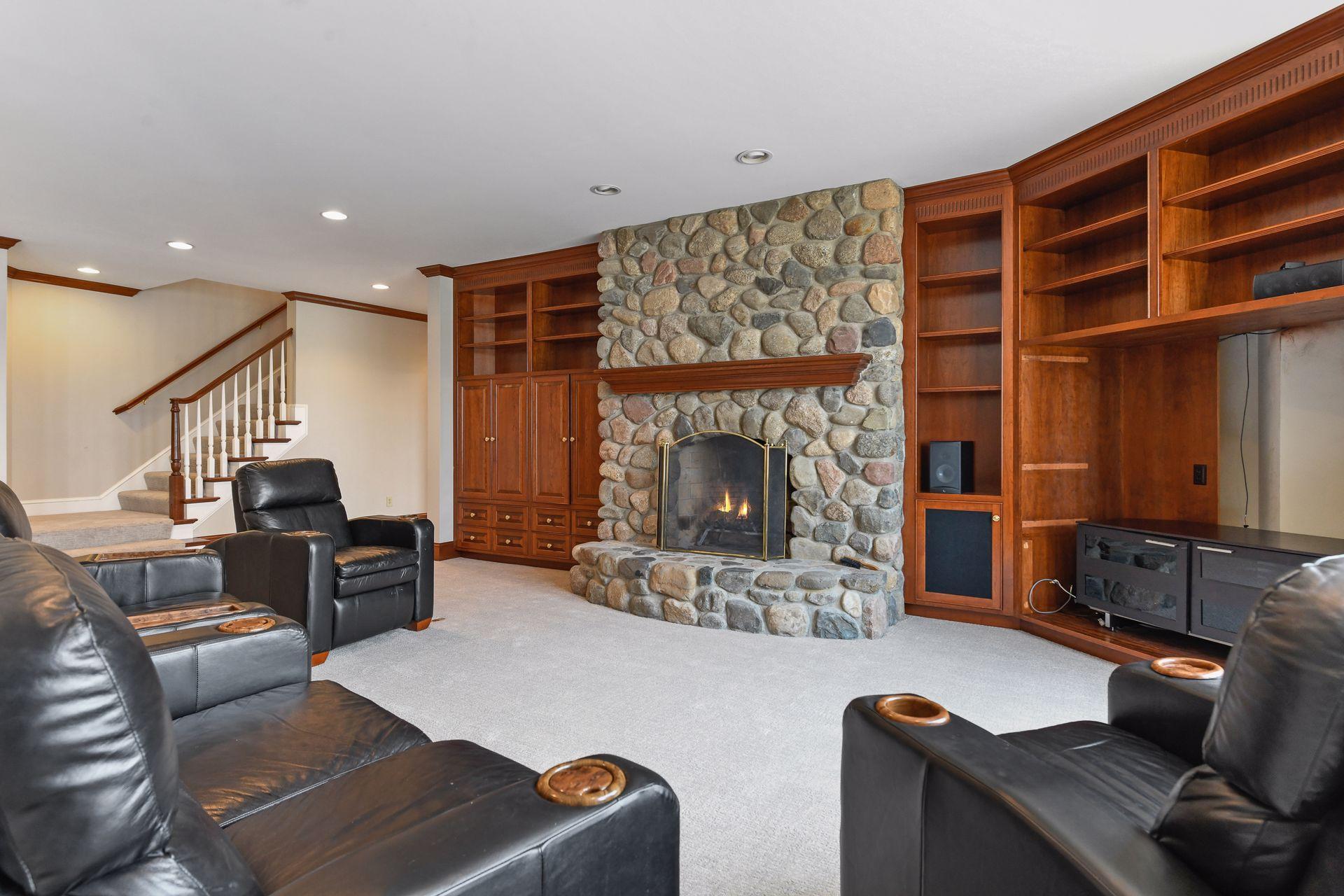 Far end of the lower level rec room is anchored by a rock faced fireplace