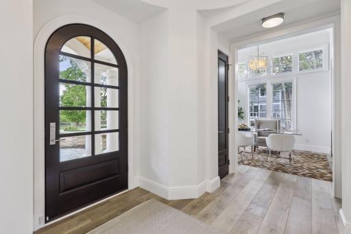 Through the large arched front door, the foyer welcomes you in a rounded entry with a wood bench and coat closet.