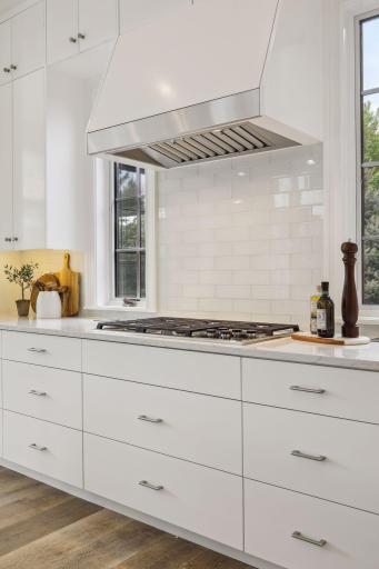 The kitchen has enameled cabinets, glass tile backsplash, and Wolf and Sub-Zero appliances.