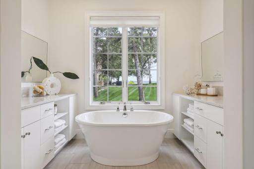 The primary bathroom is a luxurious retreat with white enamel vanities, quartz countertops, and a large soaking tub.