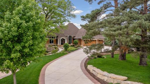 The home is at the end of a long colored decorative concrete driveway; and the exterior boasts professional landscaping, and a slate walkway leading to the arched front door, flanked by columns.
