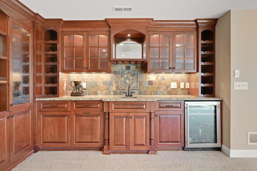 Wet bar with tons of storage, beverage fridge, stone backsplash, built-in wine holders and more!