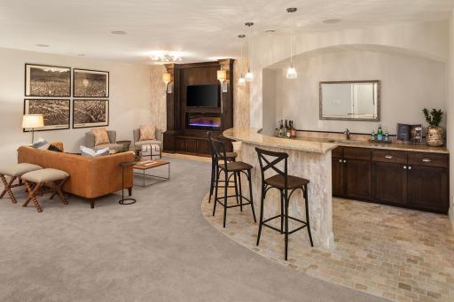 Greeted by soaring 9ft ceilings and a stunning limestone wall, the lower level features a private theater, multiple spaces for gaming, bedroom, three-quarter bath, and wine cellar.