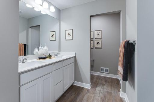 The spacious primary bath with the second walk in closet, dual vanity with quartz countertops, and large shower. Model picture shown. Colors and finishes may vary.