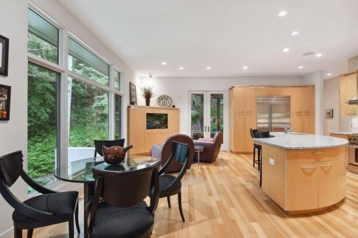 You will discover a spacious and elegant kitchen, adjoined by a welcoming hearth room. The kitchen presents a captivating display of smoothly curved cabinets, embodying a modern and sophisticated aesthetic.