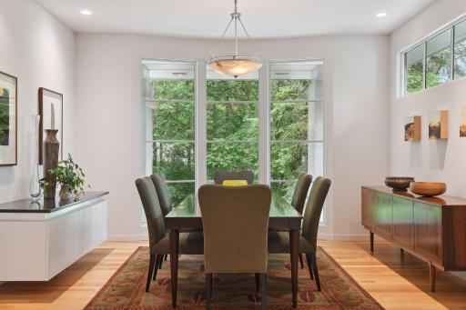 The formal dining room beckons with an abundance of light pouring in through another set of floor-to-ceiling windows, offering enchanting views of the front columns and meticulously landscaped grounds.