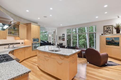 Bathed in abundant natural light pouring through the numerous windows, the kitchen presents breathtaking vistas of the surrounding landscape, seamlessly merging indoor and outdoor elements.