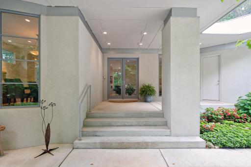 Flanked by tall stucco columns, the glass French doors at the front entrance exude an air of elegance and grandeur, offering a glimpse of the remarkable interior that awaits.