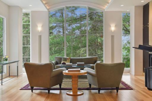 Floor-to-ceiling windows grace the room, framing a mesmerizing view of the verdant, wooded yard. The abundant natural light bathes the room, suffusing it with a sense of spaciousness and airiness.