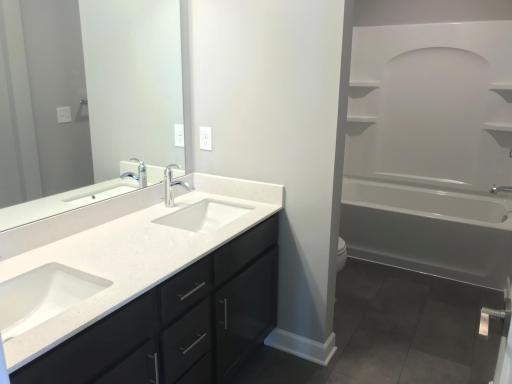 Secondary upper level bath with dual vanities and separate shower area. Finishes will vary.